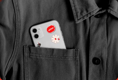 Celular com adesivos da Althos no bolso de uma jaqueta